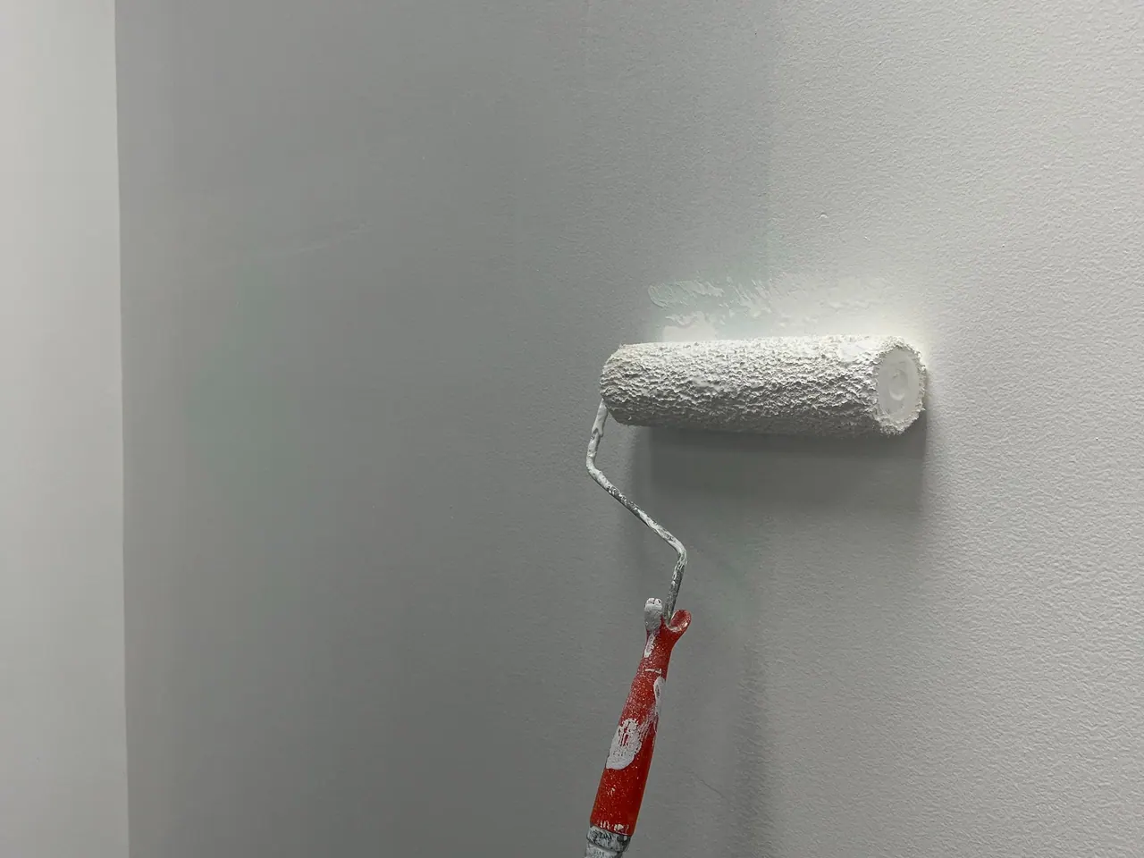Frisch weiß gestrichene Wand mit Farbrolle