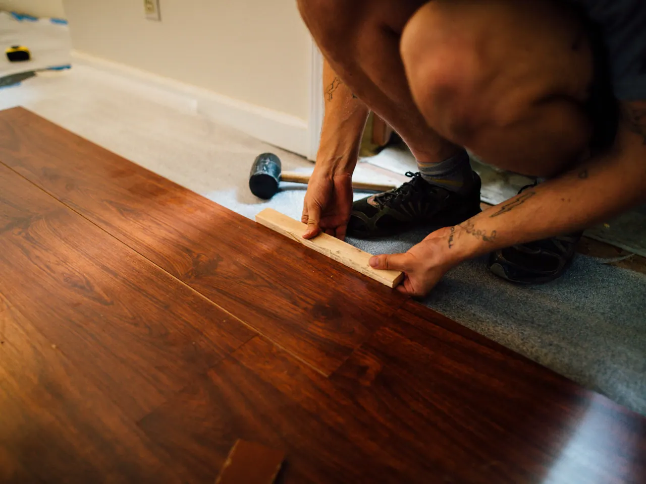 Hände verlegen Laminatdielen mit Schlagholz