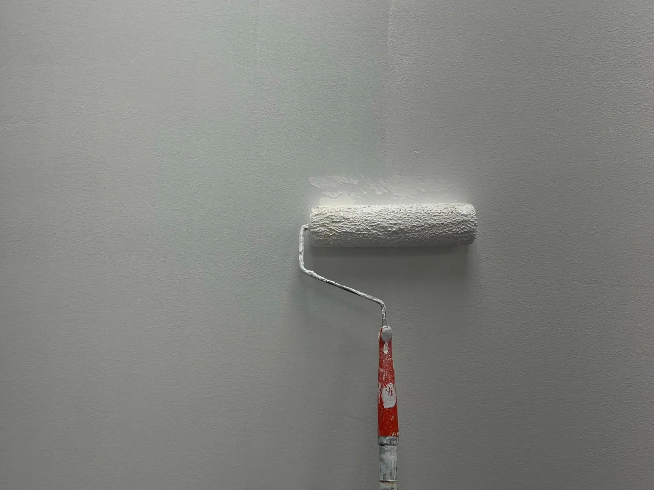 Farbrolle mit heller Farbe an einer Wand